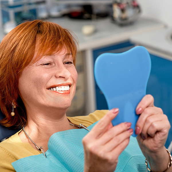 A woman at the dentist looking at her smile in a mirror