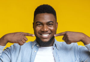 Closeup of a Black young man smiling against a yellow background