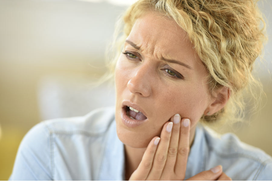 woman holds her jaw in pain from tooth sensitivity