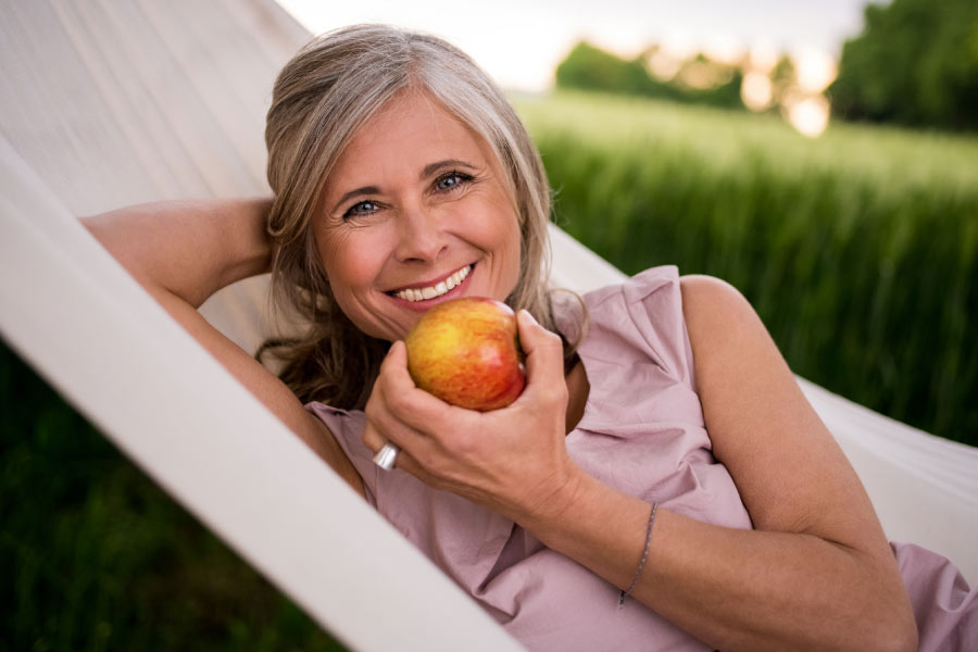 woman on a lounge chair eating an apple